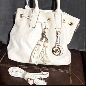 White purse, with shoulder strap, has handles